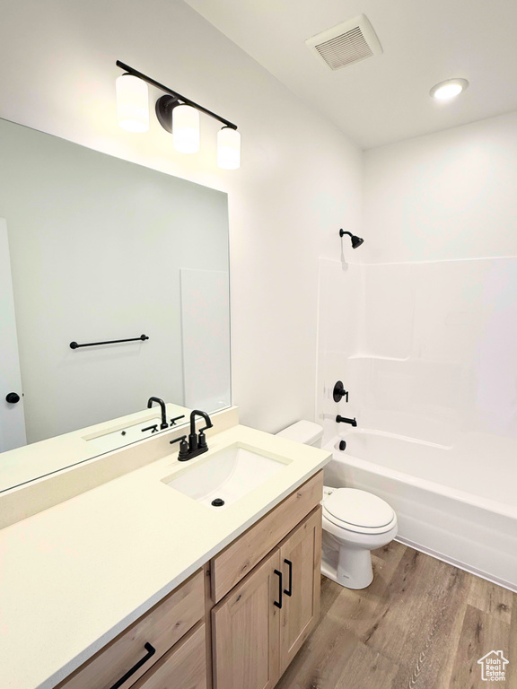 Full bathroom with wood finished floors, toilet, vanity, and tub / shower combination