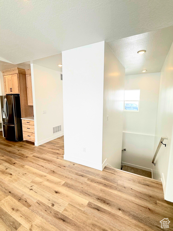Staircase with a textured ceiling, wood finished floors, and baseboards