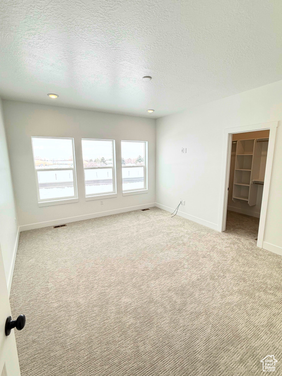 Unfurnished room featuring light carpet, a textured ceiling, baseboards, and recessed lighting