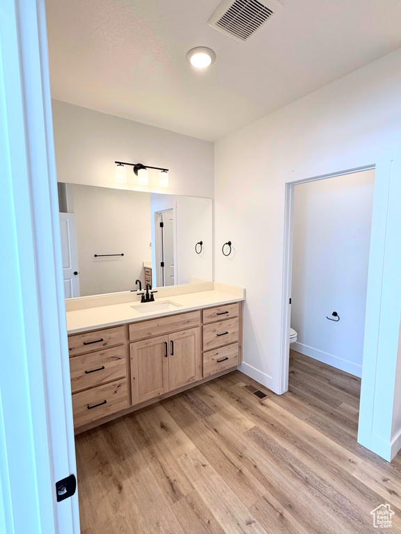 Bathroom with toilet, wood finished floors, vanity, and baseboards