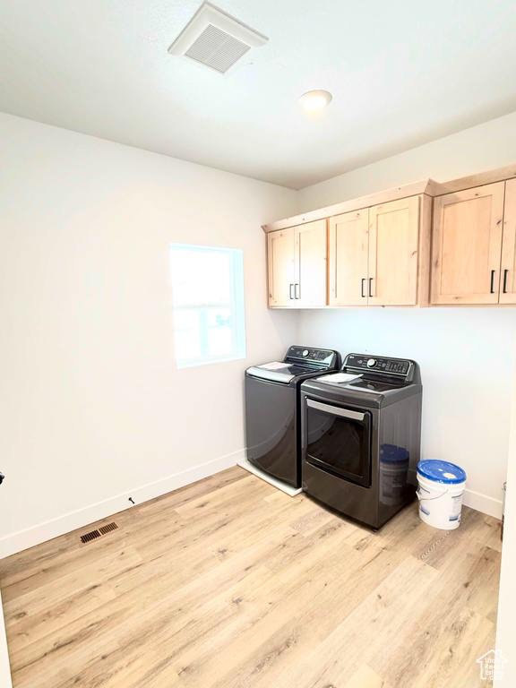 Laundry area featuring cabinet space, washer and dryer, light wood-type flooring, and baseboards