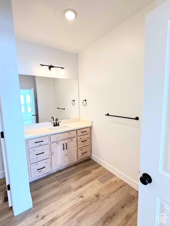 Bathroom featuring wood finished floors, vanity, and baseboards