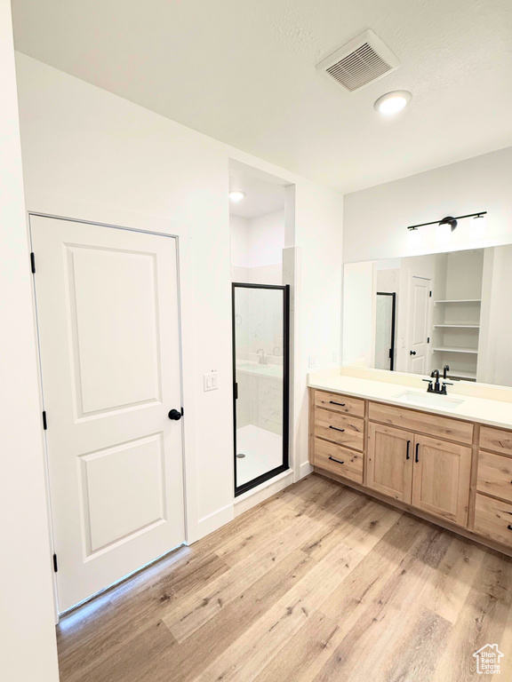 Full bathroom featuring wood finished floors, a shower stall, and vanity
