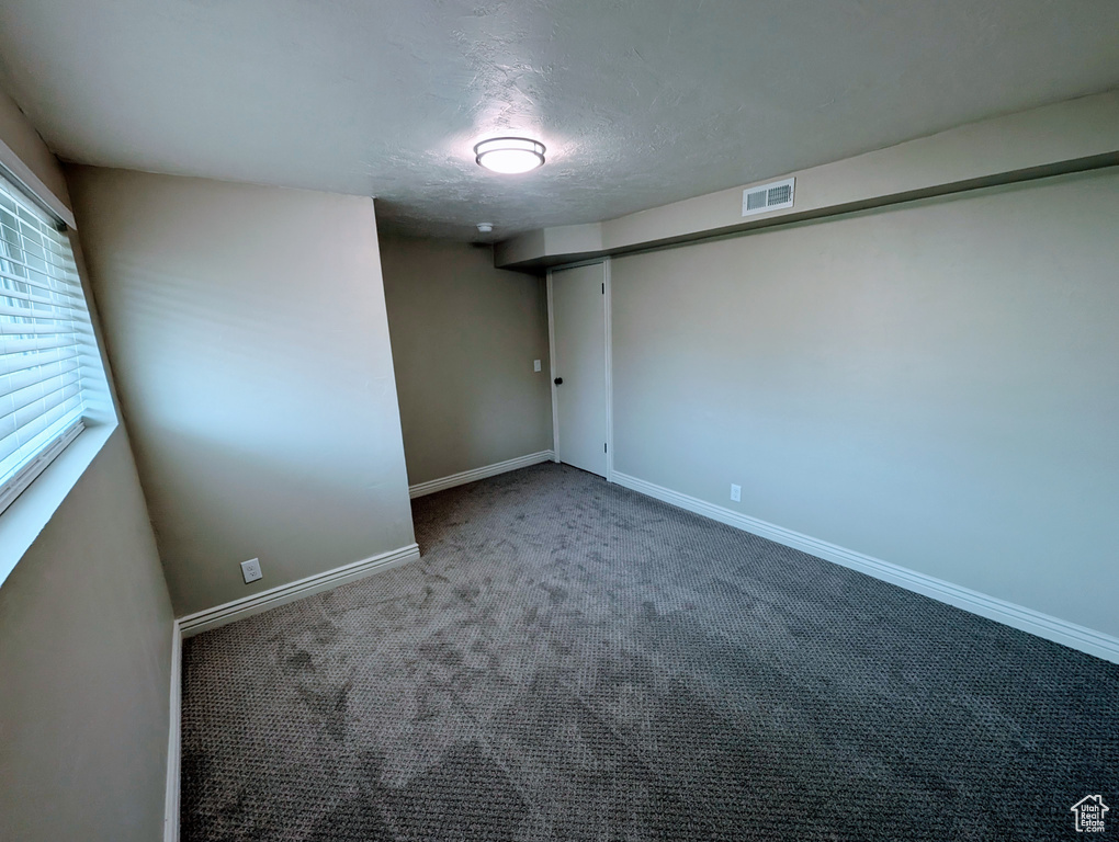 Unfurnished room with carpet flooring, baseboards, and a textured ceiling