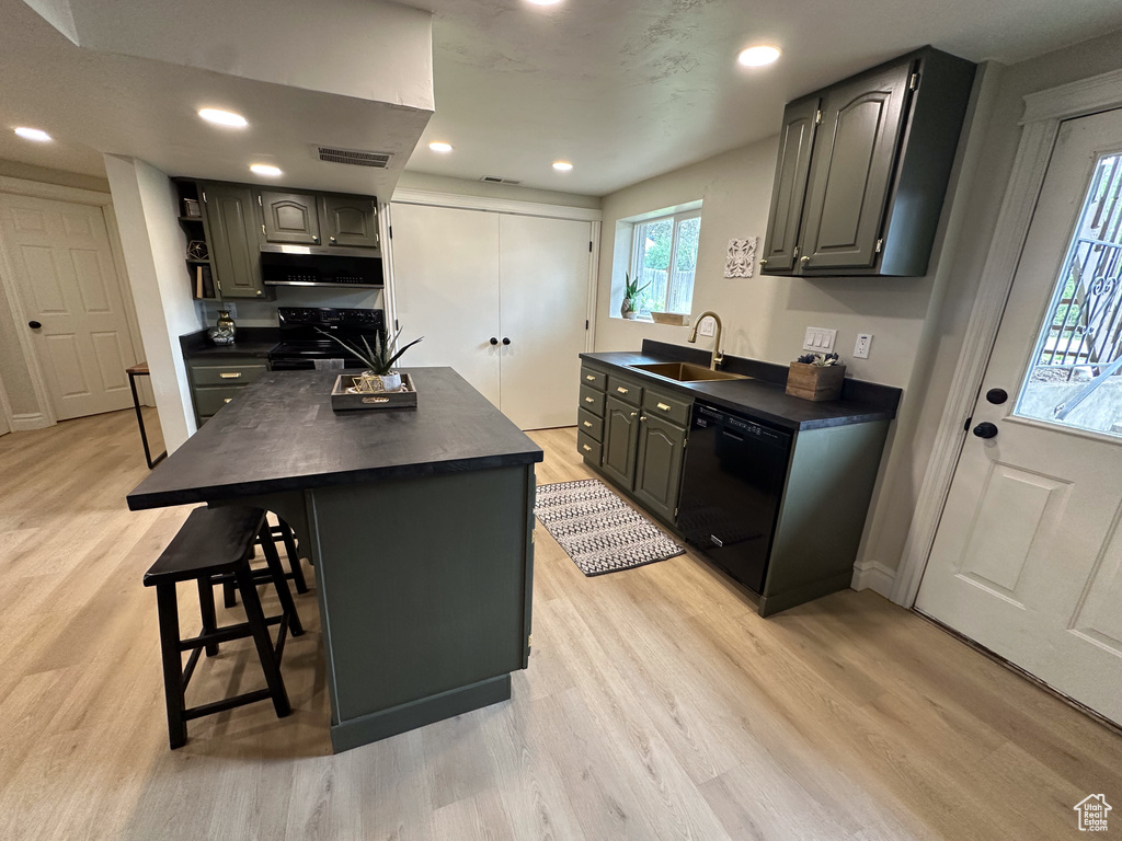 Kitchen with black appliances, dark countertops, a sink, light wood finished floors, and recessed lighting