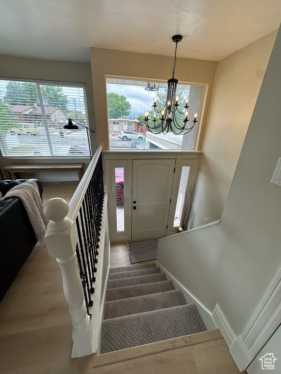 Stairs with a chandelier and wood finished floors