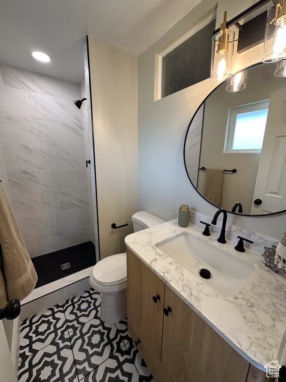 Full bathroom featuring toilet, tiled shower, and vanity
