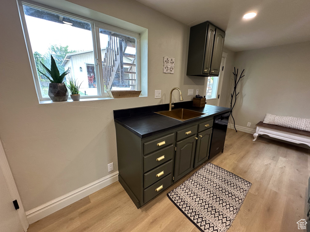 Kitchen featuring a sink, dark countertops, light wood-style floors, baseboards, and recessed lighting