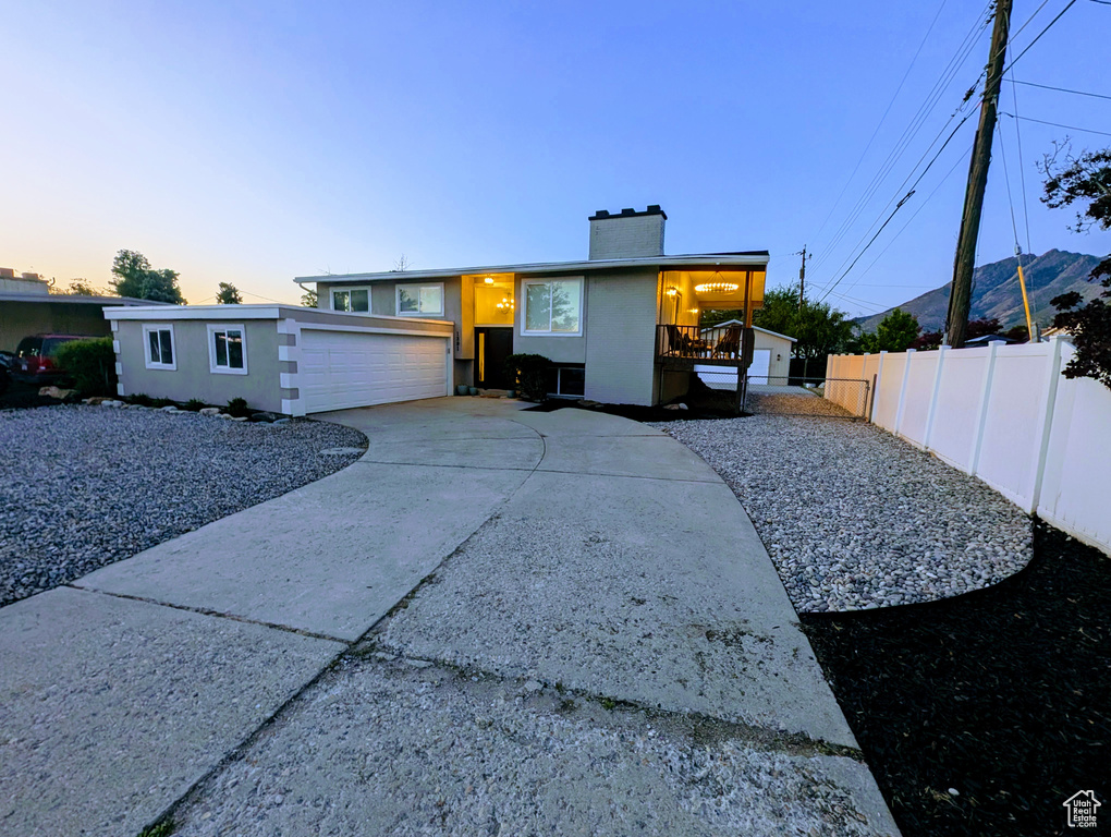 View of front of home with a chimney, driveway, and stucco siding