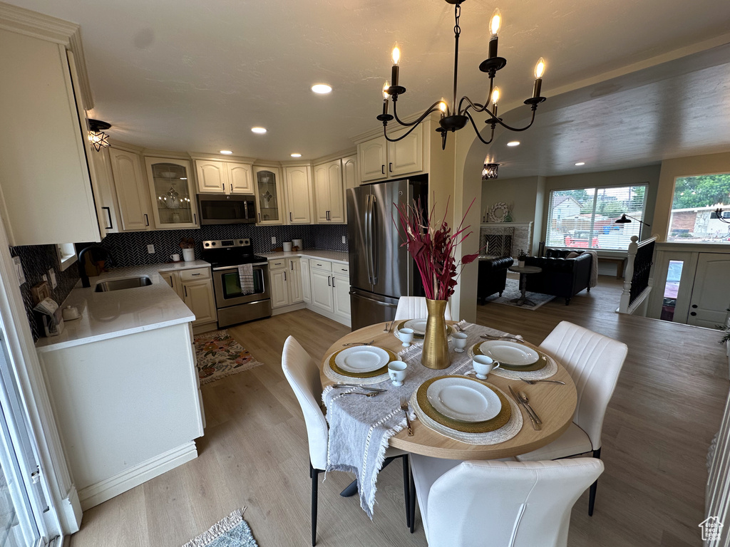 Dining space featuring light wood-type flooring, a fireplace, a chandelier, and recessed lighting