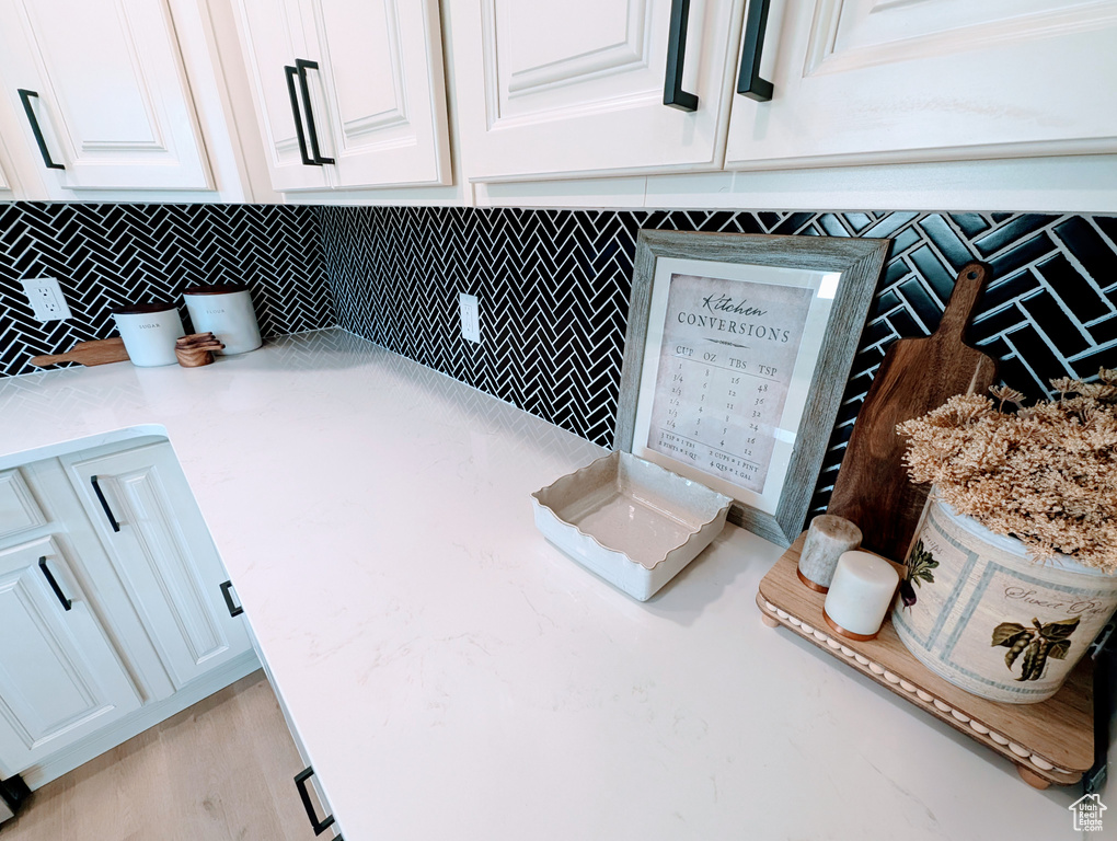Kitchen view of white cabinetry, backsplash, and light stone counters