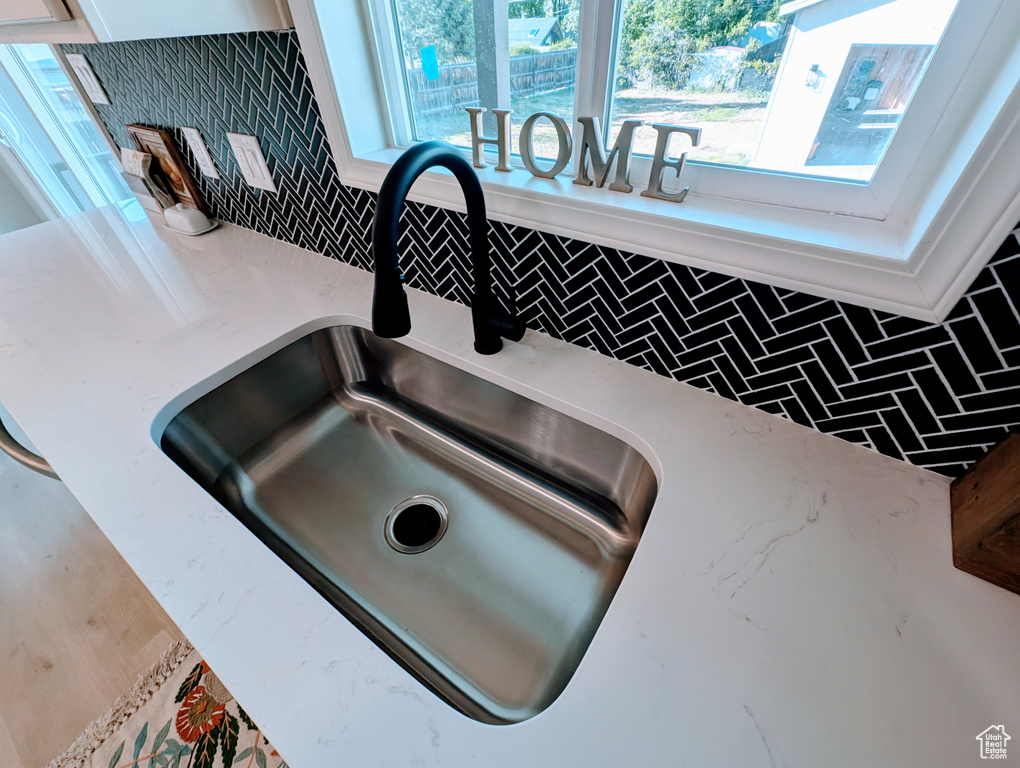 Kitchen view of a sink, backsplash, and white cabinetry