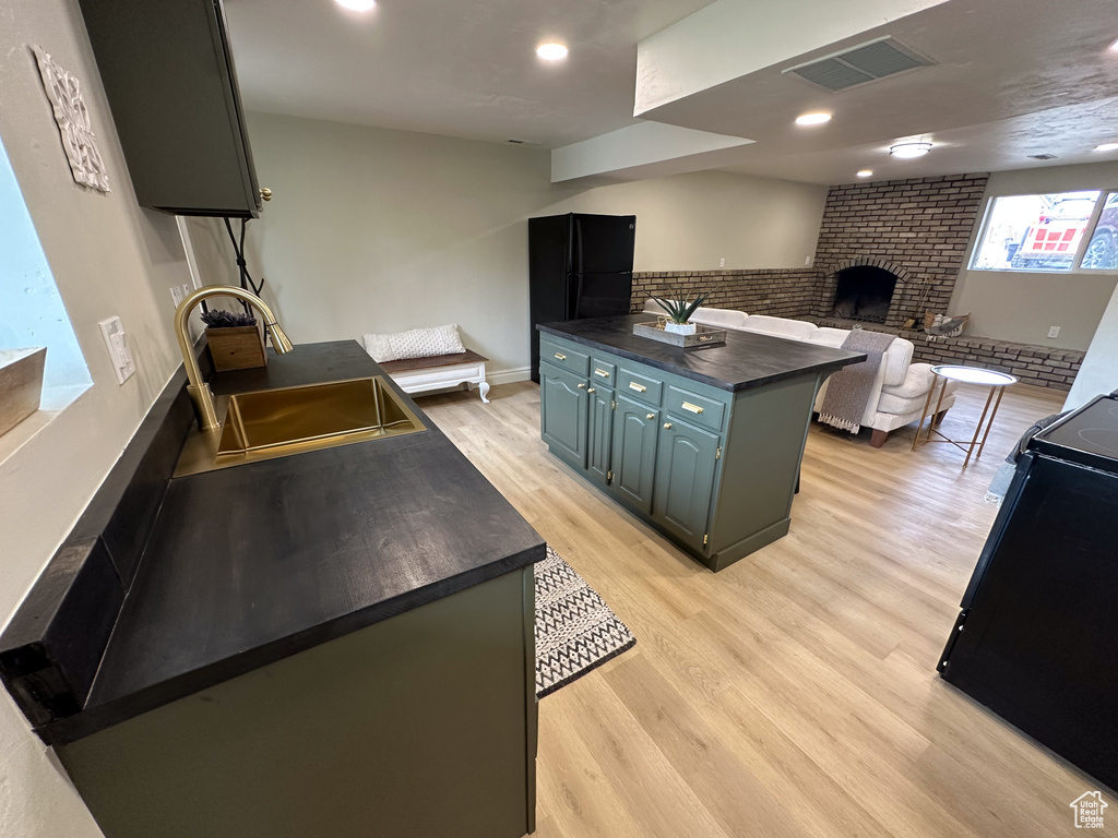 Kitchen with dark countertops, range, a sink, light wood finished floors, and open floor plan