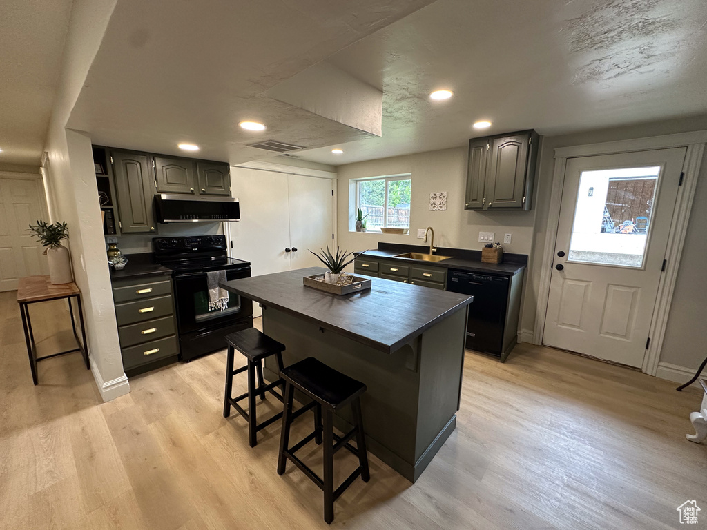 Kitchen featuring black appliances, a sink, extractor fan, light wood-style flooring, and recessed lighting
