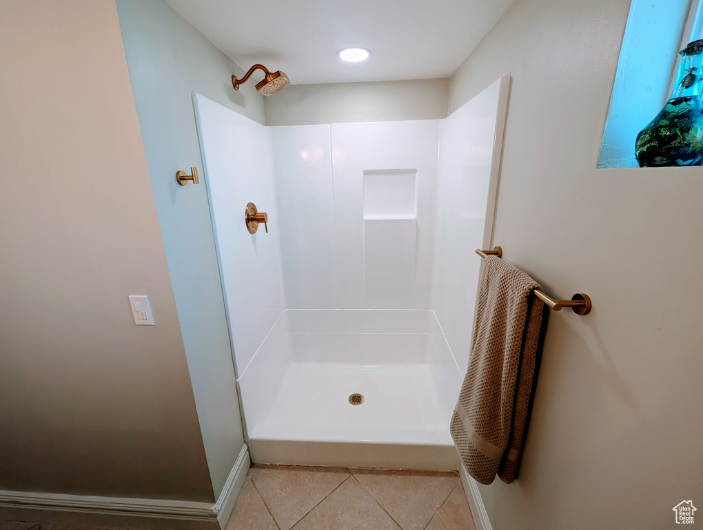 Full bathroom featuring tile patterned floors, a shower, and baseboards