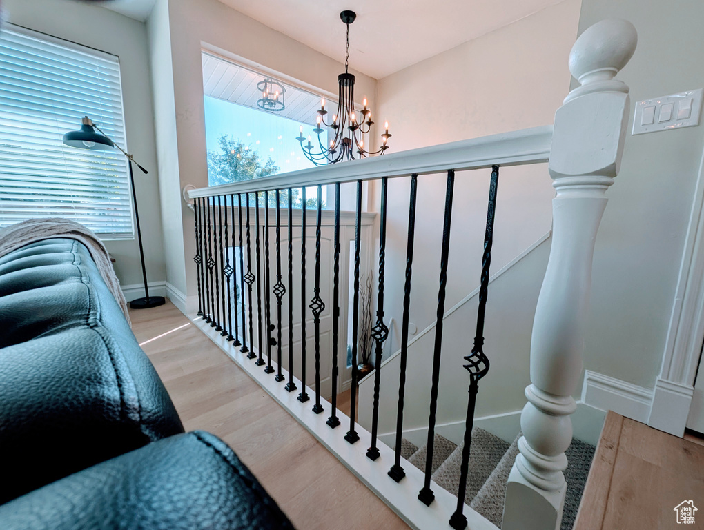Stairway with wood finished floors, a chandelier, and baseboards