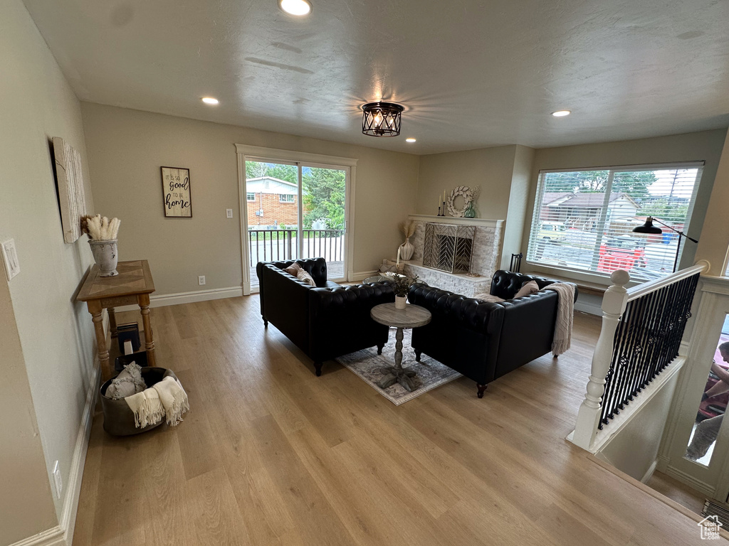 Living area featuring light wood-type flooring, a stone fireplace, recessed lighting, and baseboards
