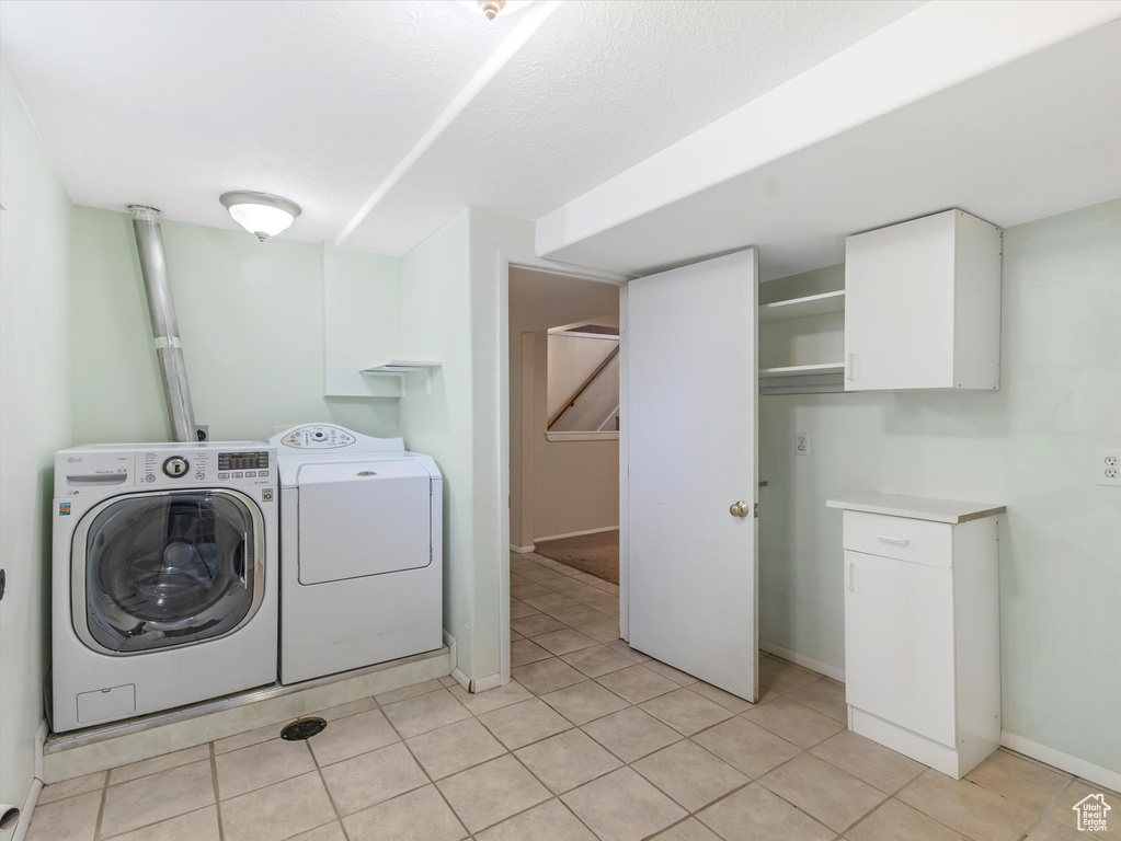 Laundry room with washing machine and dryer, light tile patterned floors, and baseboards