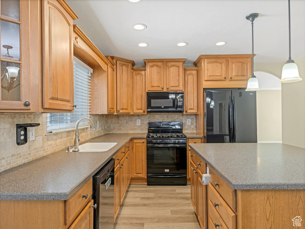 Kitchen with black appliances, a sink, light wood finished floors, recessed lighting, and tasteful backsplash