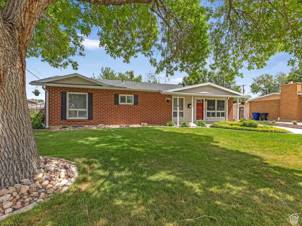 Single story home featuring brick siding, a front lawn, and a porch