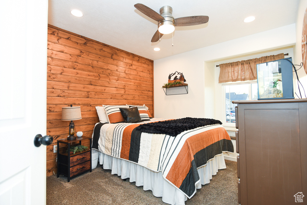 Carpeted bedroom with wooden walls, recessed lighting, and a ceiling fan