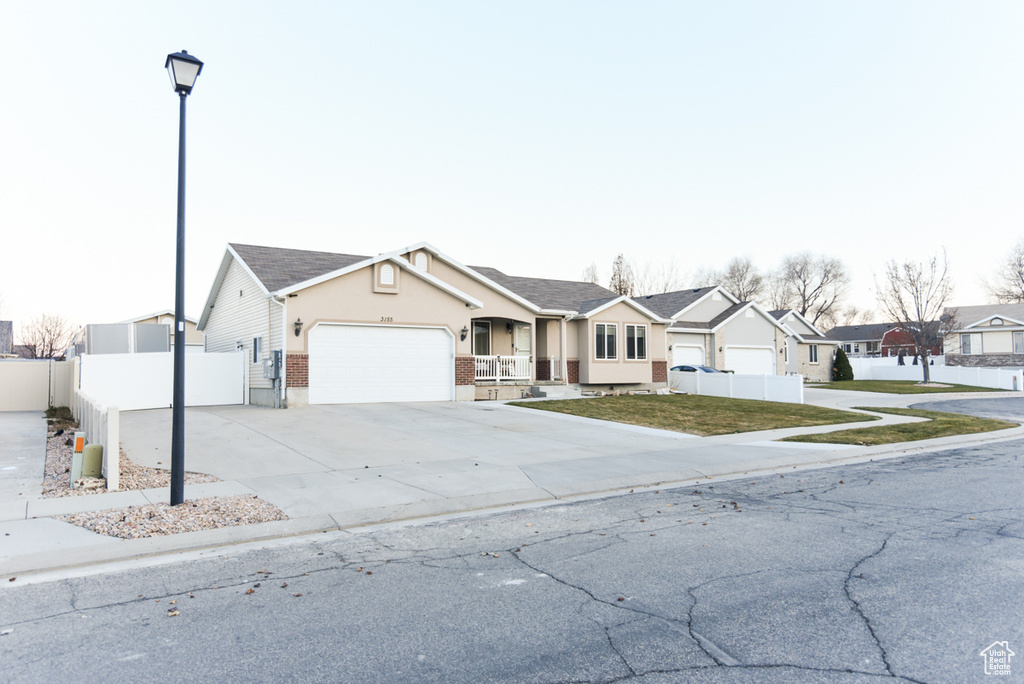 Ranch-style house with an attached garage, a residential view, driveway, a porch, and stucco siding