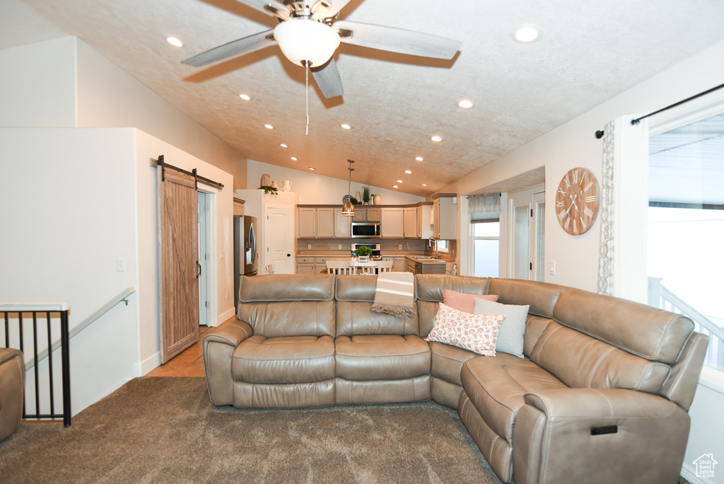 Carpeted living room featuring recessed lighting, ceiling fan, a barn door, and lofted ceiling