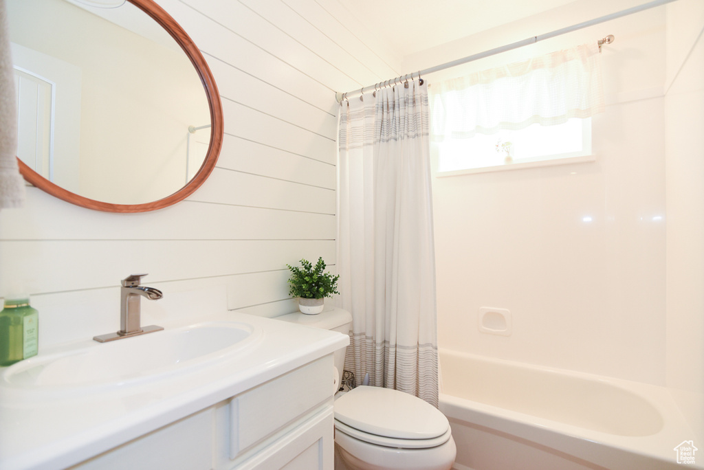Bathroom with toilet, vanity, shower / bathtub combination with curtain, and wood walls