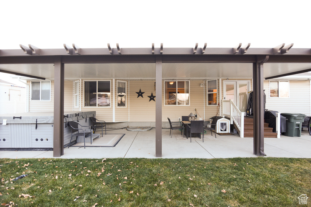 Rear view of property featuring a lawn, entry steps, and a patio area