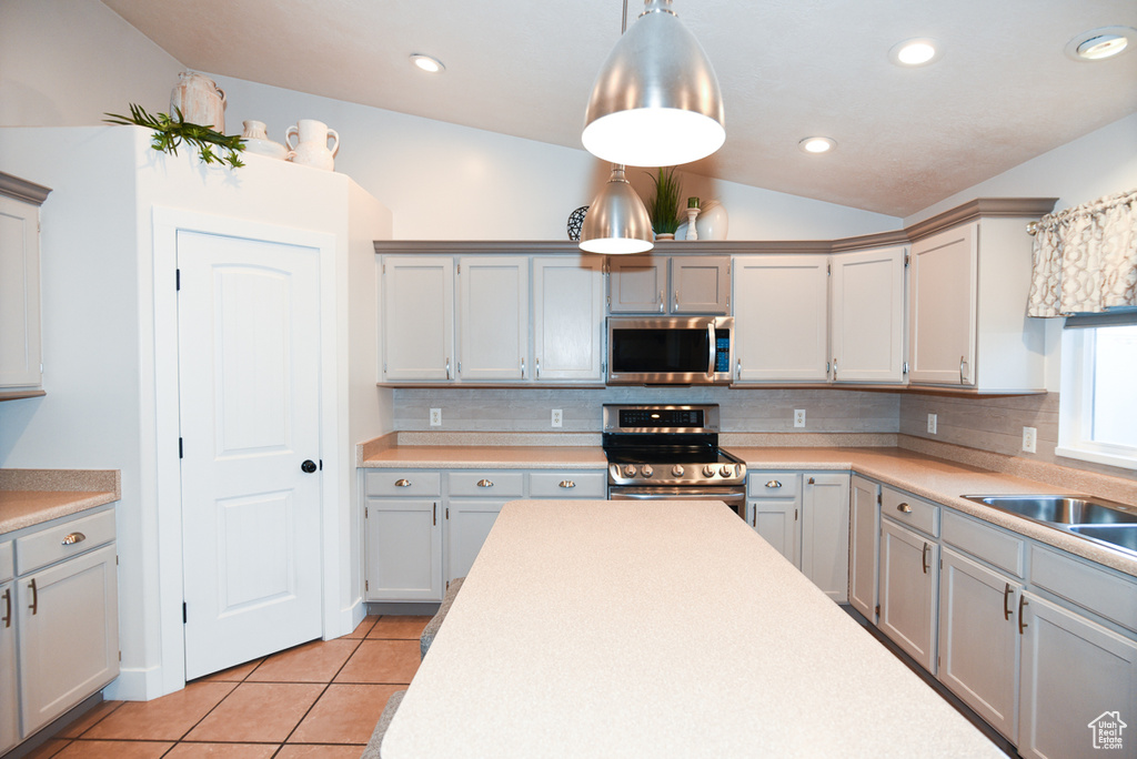 Kitchen with appliances with stainless steel finishes, decorative backsplash, light tile patterned floors, light countertops, and lofted ceiling