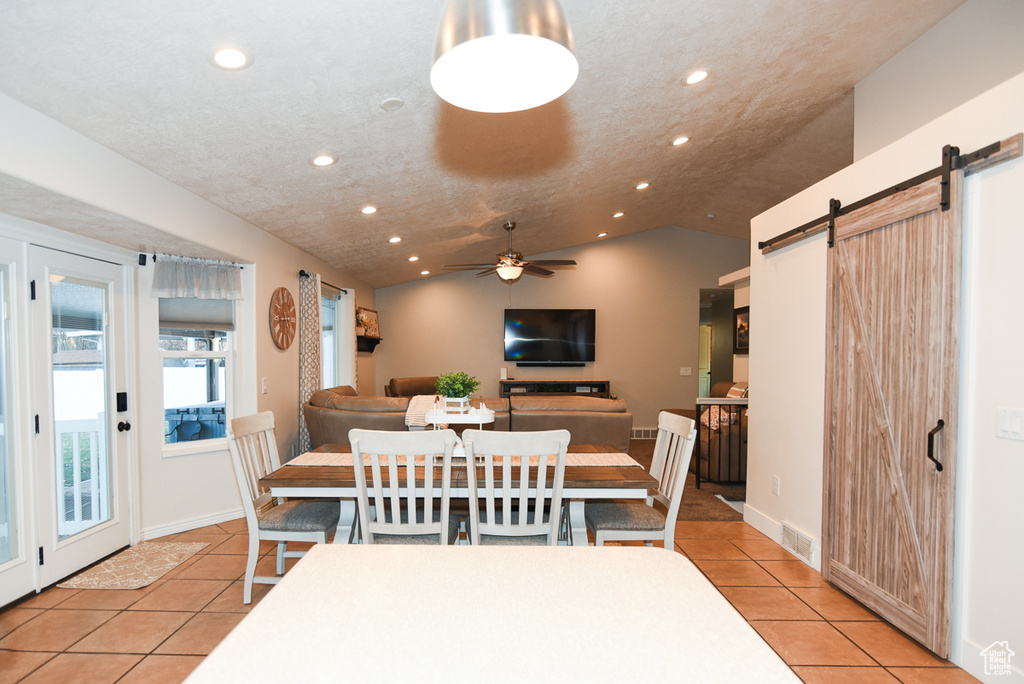 Dining area featuring a barn door, light tile patterned floors, recessed lighting, lofted ceiling, and a ceiling fan