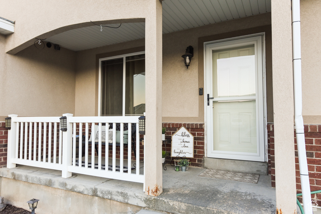 Entrance to property featuring covered porch and stucco siding