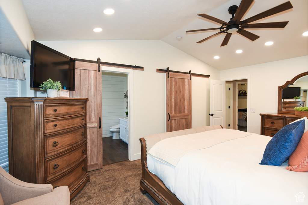 Bedroom featuring a barn door, vaulted ceiling, recessed lighting, dark colored carpet, and connected bathroom