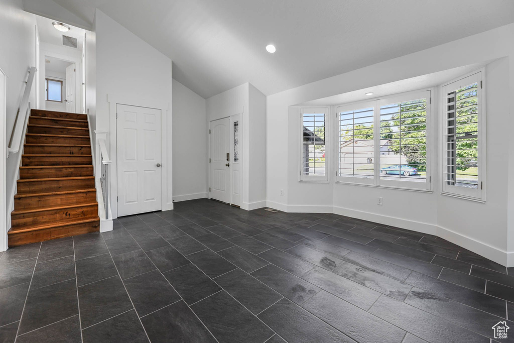 Unfurnished living room with lofted ceiling, stairway, baseboards, and recessed lighting
