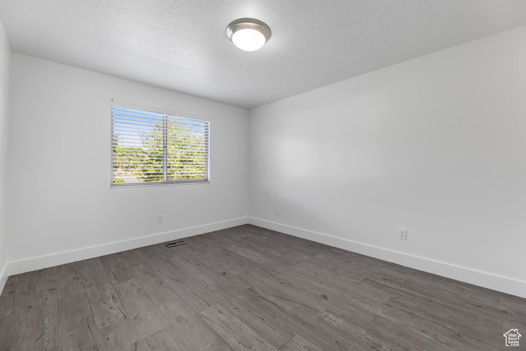 Spare room with baseboards, dark wood-style floors, and a textured ceiling