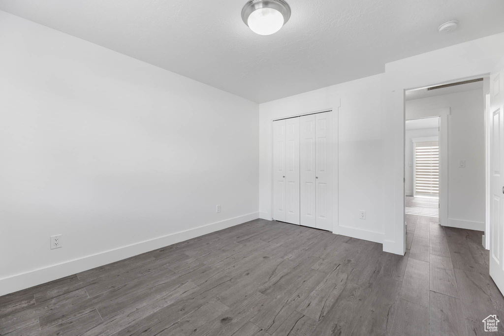 Unfurnished bedroom with baseboards, a closet, and dark wood-style floors