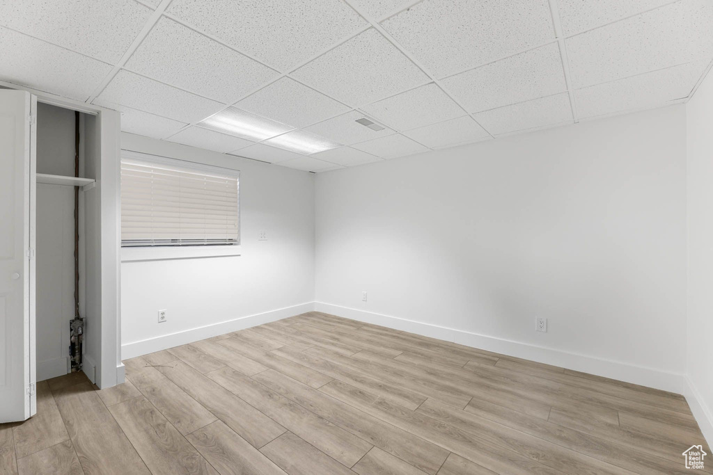 Unfurnished bedroom with a paneled ceiling, light wood-type flooring, and baseboards