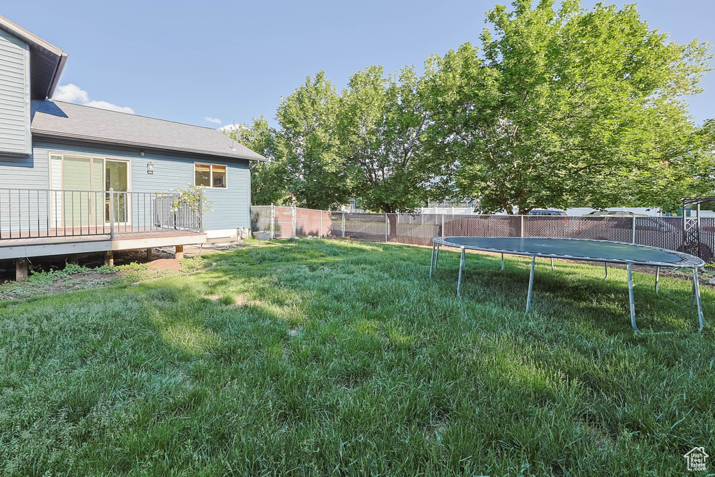 View of yard featuring a trampoline and a deck