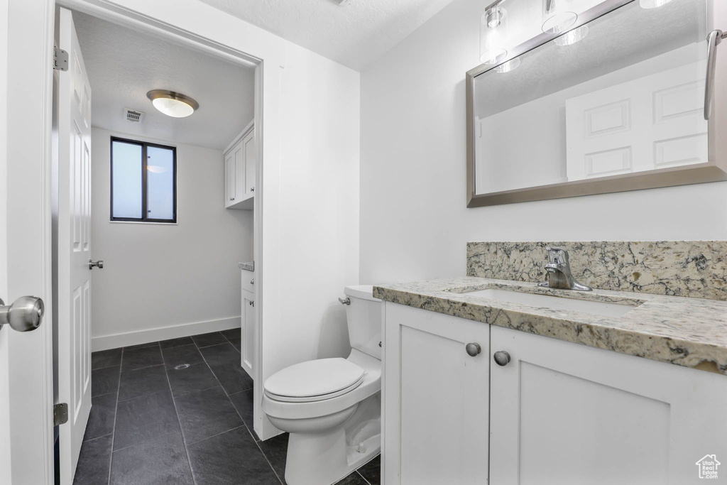 Bathroom featuring vanity, toilet, tile patterned floors, and baseboards