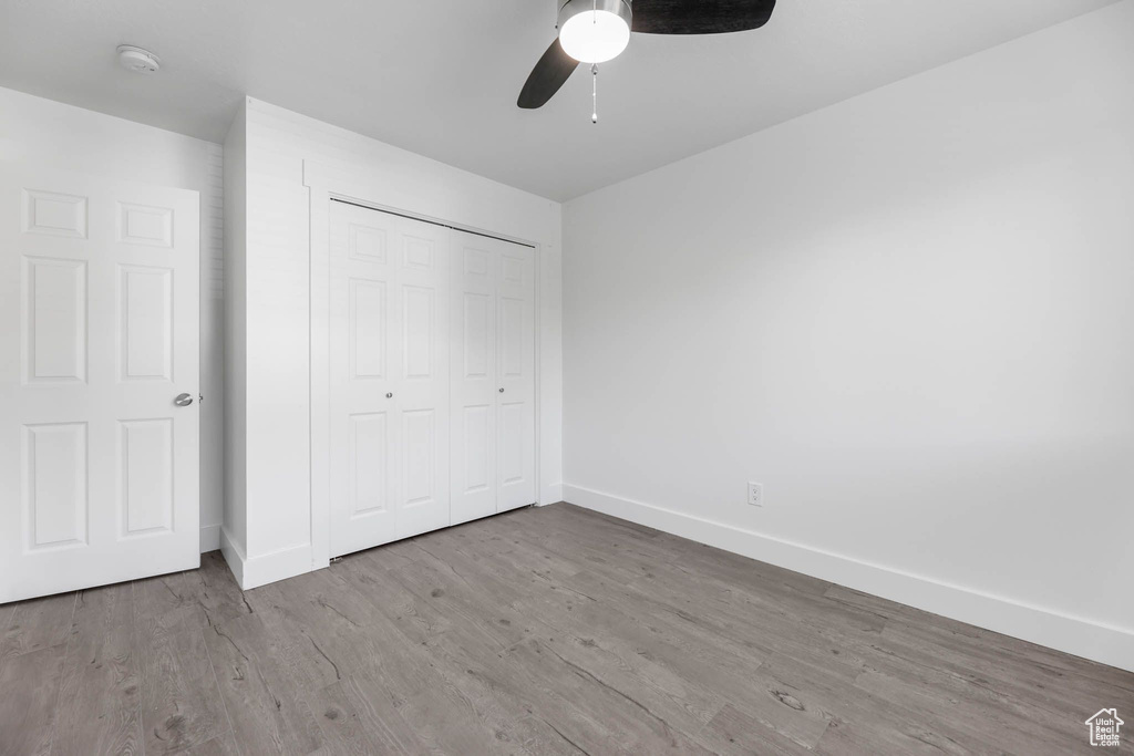 Unfurnished bedroom featuring baseboards, wood finished floors, a closet, and ceiling fan