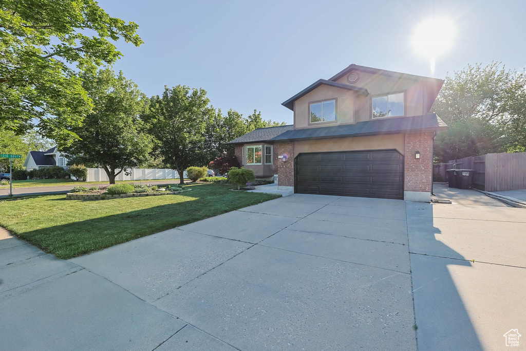 Traditional-style home with an attached garage, concrete driveway, and brick siding
