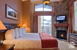 Bedroom with a stone fireplace and vaulted ceiling