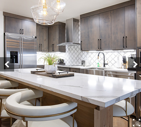 Kitchen featuring wall chimney range hood, appliances with stainless steel finishes, a sink, and dark brown cabinetry
