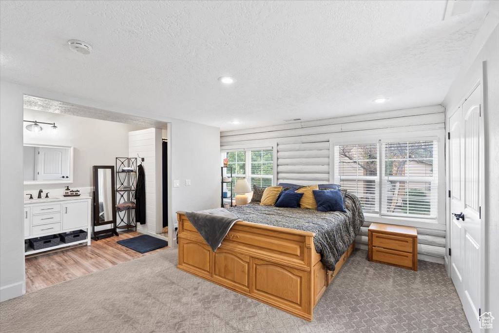 Bedroom with a textured ceiling, a sink, recessed lighting, light wood-style flooring, and light carpet