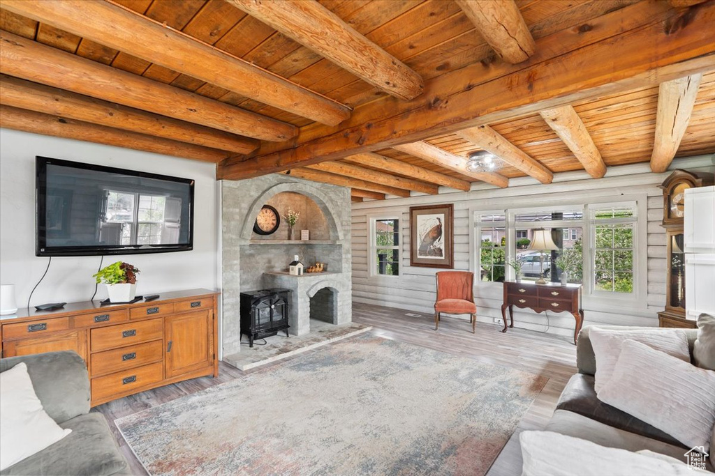 Living area featuring wood ceiling with exposed beams, wood finished floors, and a wood stove