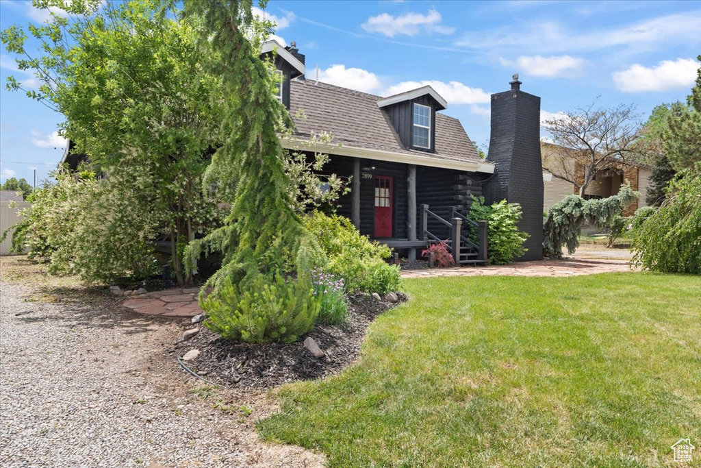 View of front of house featuring a chimney, a front yard, and log siding