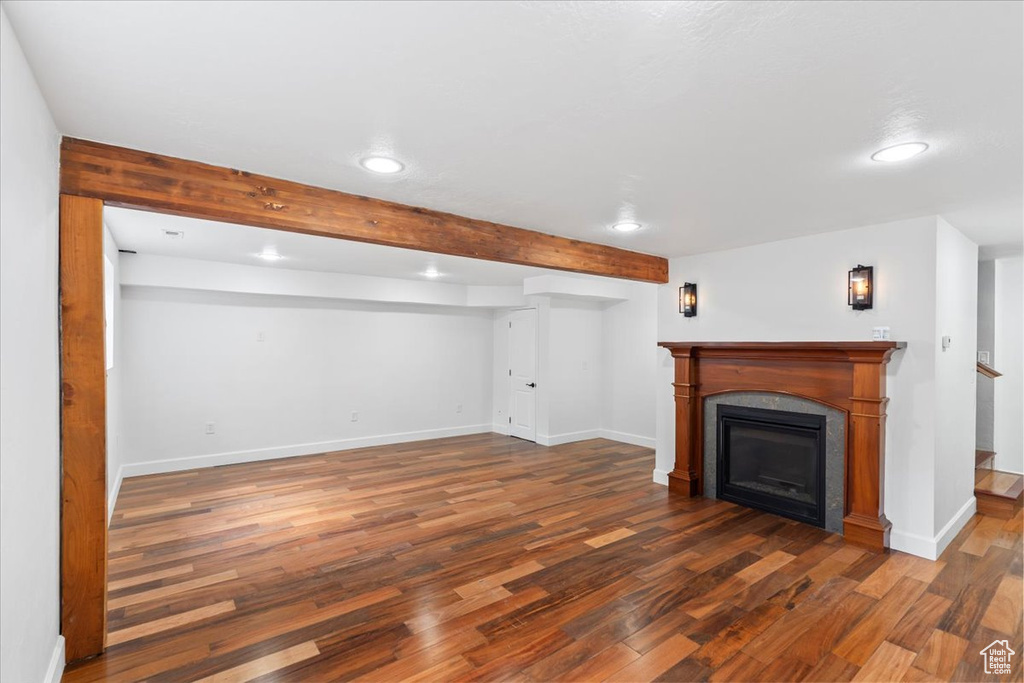 Unfurnished living room featuring wood finished floors, recessed lighting, baseboards, beam ceiling, and a fireplace