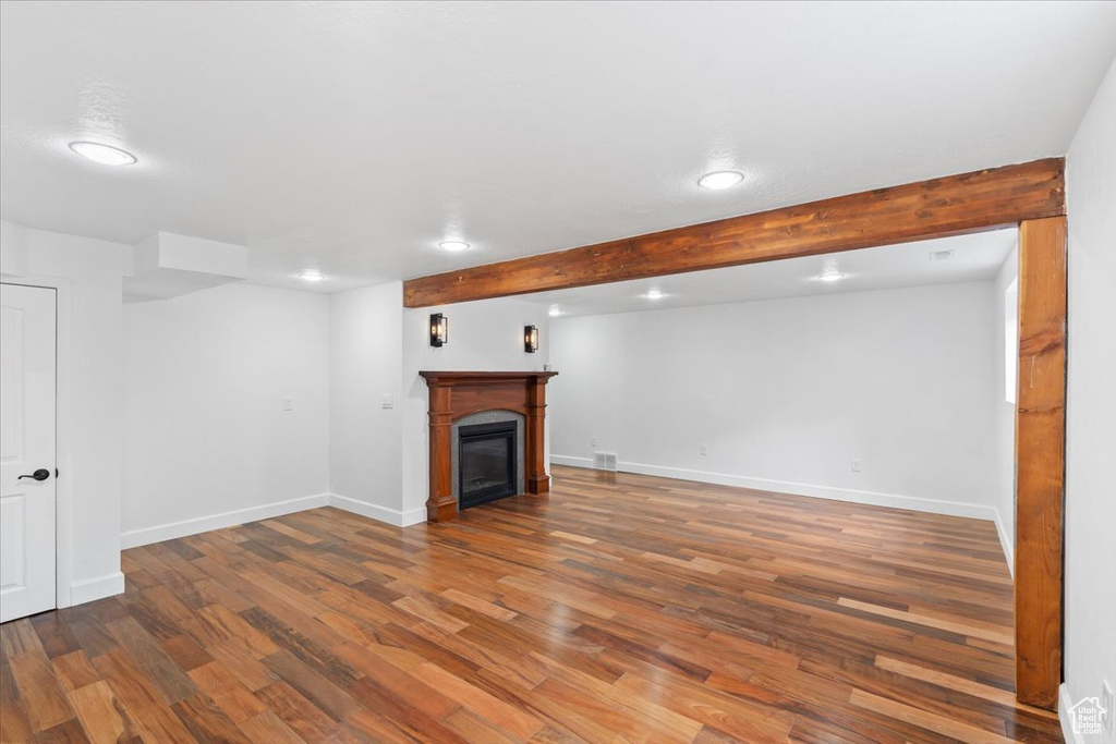Finished below grade area featuring recessed lighting, wood finished floors, baseboards, and a glass covered fireplace