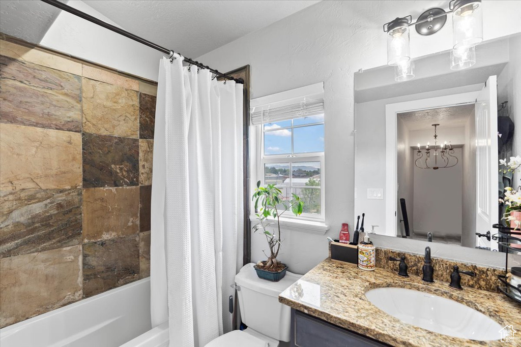 Bathroom featuring toilet, shower / bath combination with curtain, vanity, and a chandelier