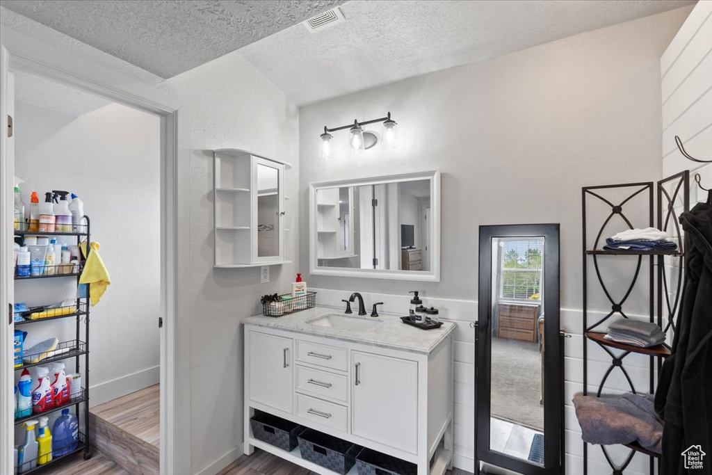 Bathroom with a textured ceiling, wood finished floors, and vanity